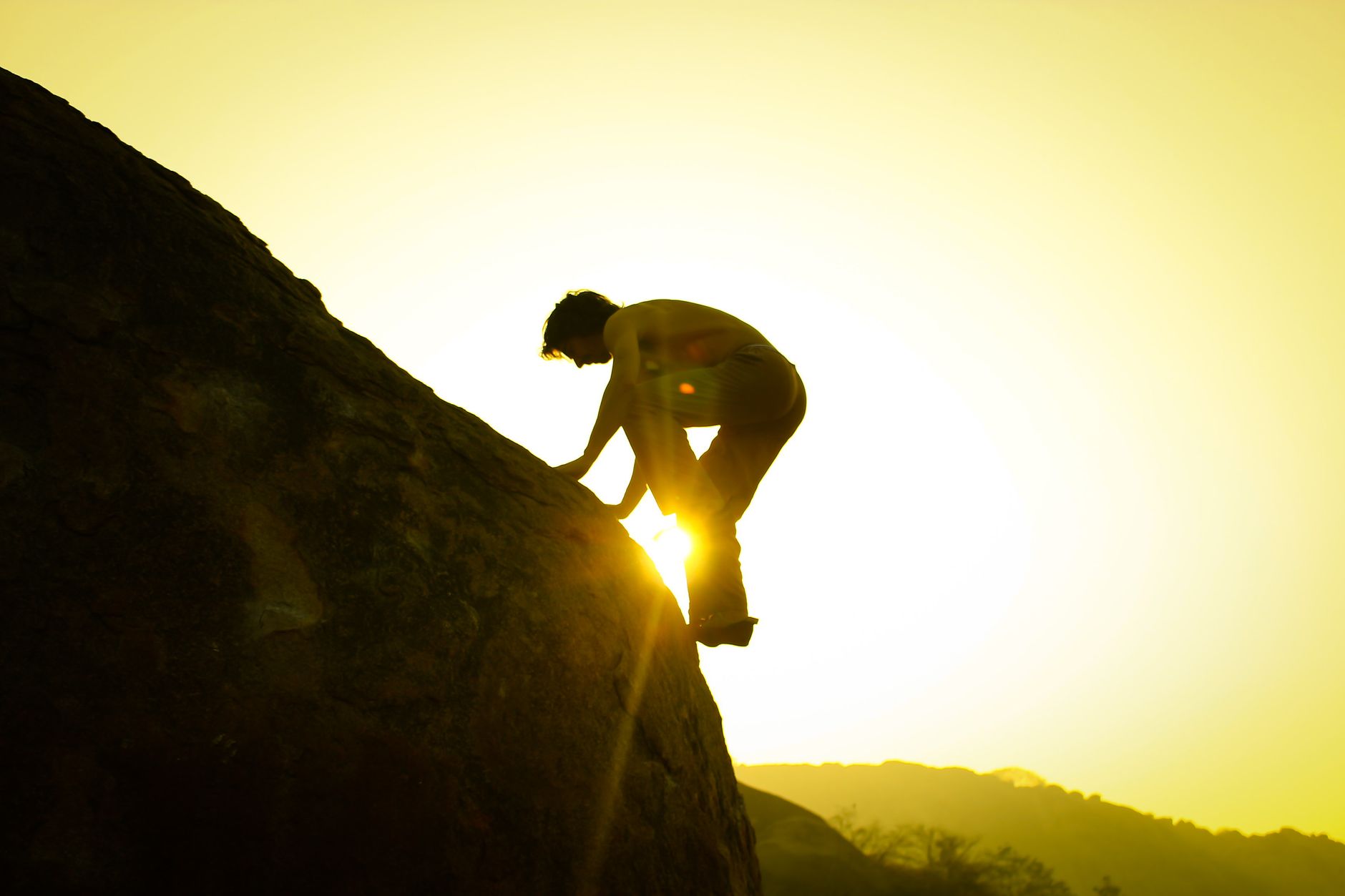 man climbing rock at dusk